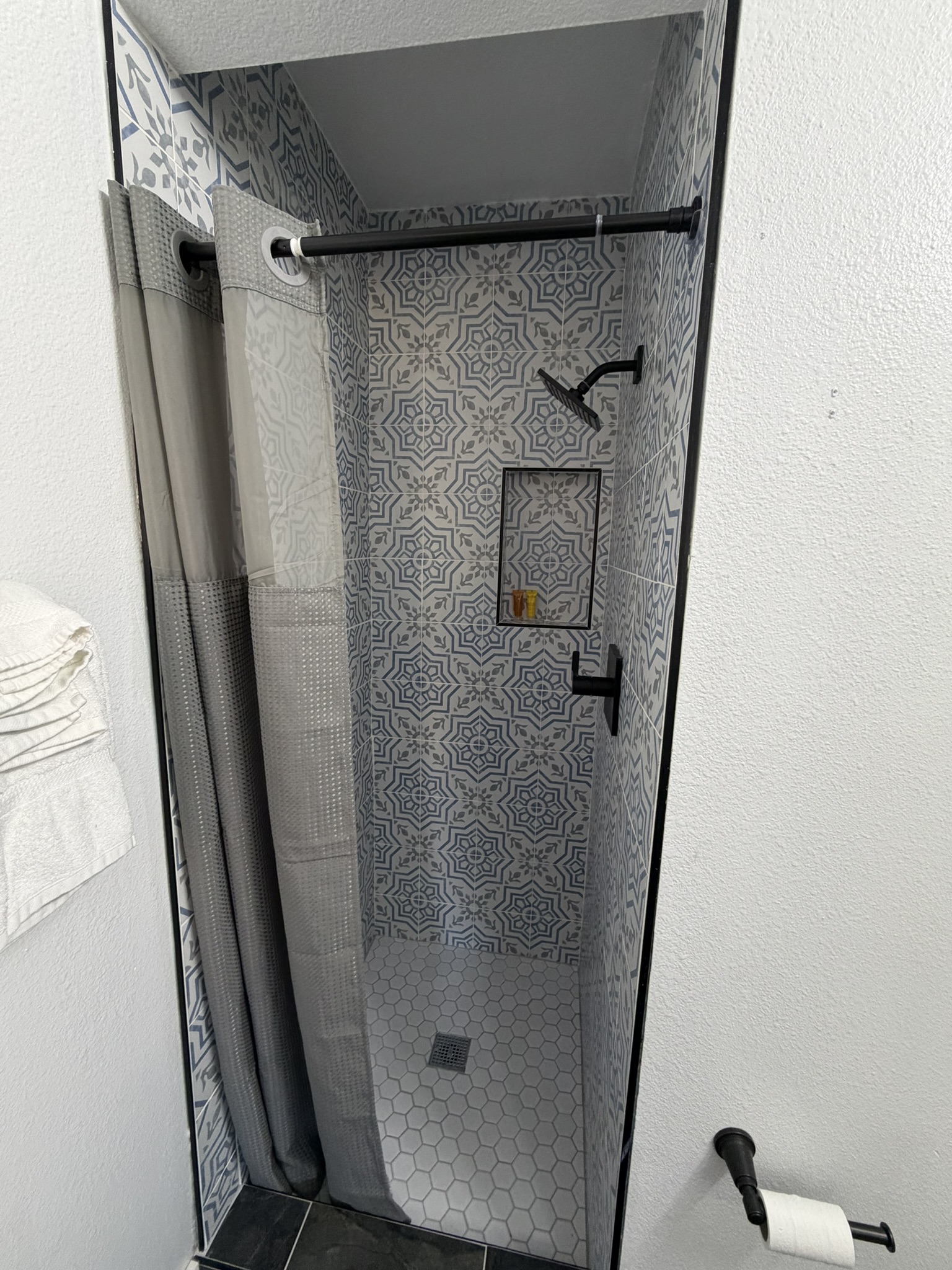 Renovated walk-in shower with patterned tile and matte-black fixtures