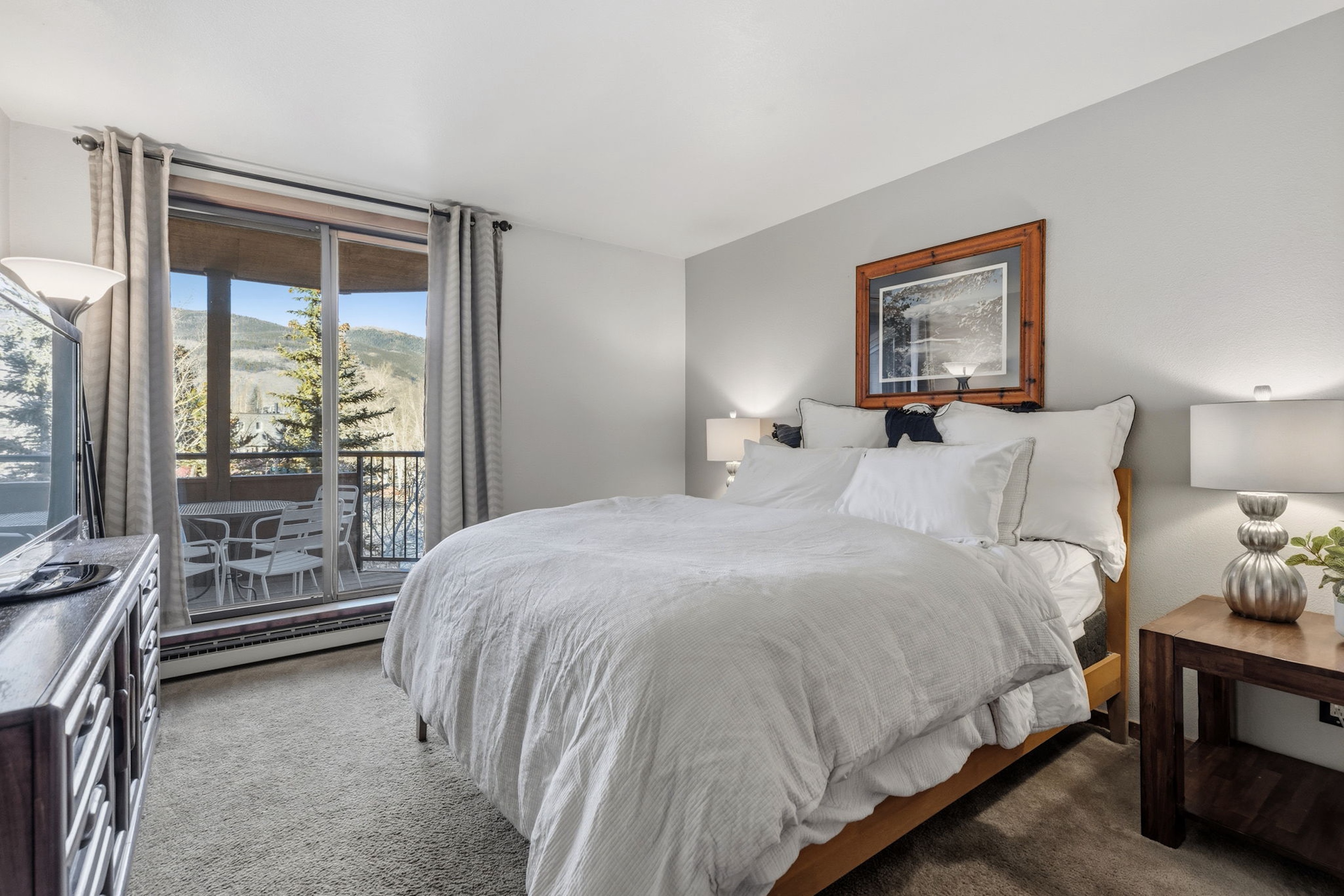 Bright primary bedroom with a private balcony and mountain view